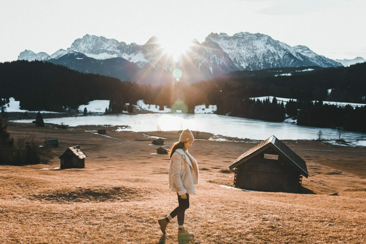 Glow by G Holiday Season header image, girl in winter clothes walking near a frozen lake with snow covered mountains in background